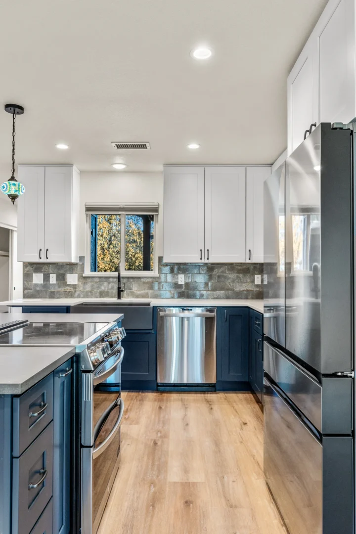 Kitchen remodel in Flagstaff AZ with two-tone navy and white cabinets, stone backsplash, and stainless appliances by Barden Home Builders