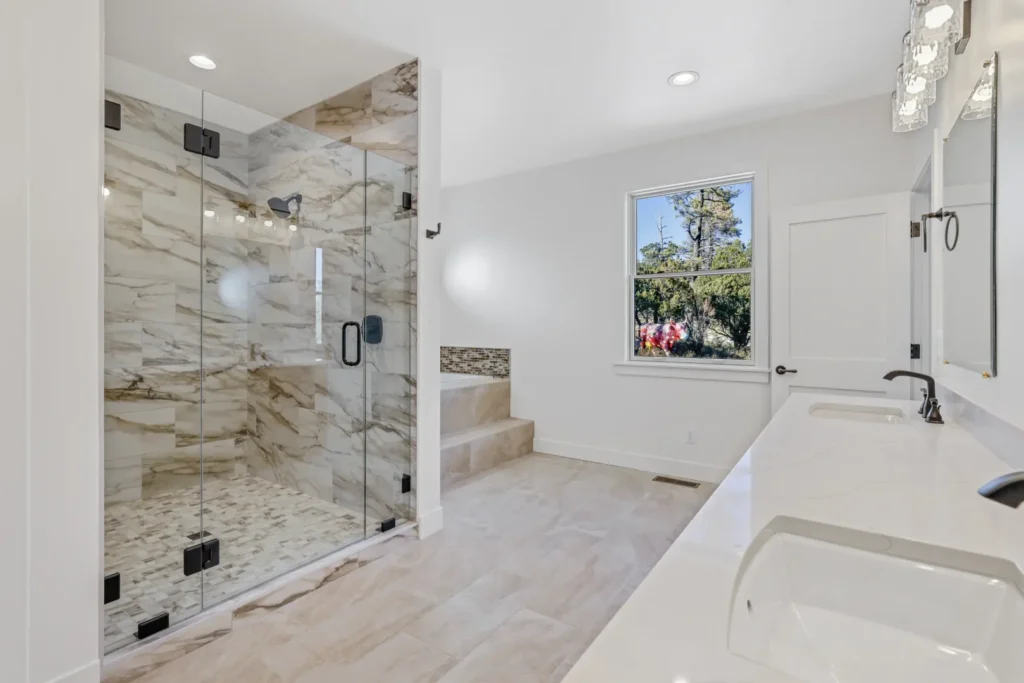 Flagstaff primary bathroom remodel featuring floor-to-ceiling marble tile shower, freestanding soaking tub, and quartz vanity by Barden Home Builders